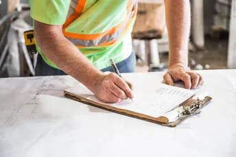 man writing on note pad in construction gear